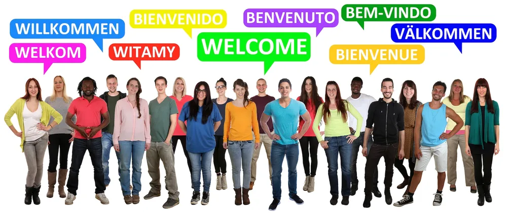 Diverse people holding speech bubbles saying welcome in different languages - representing different accents and language backgrounds